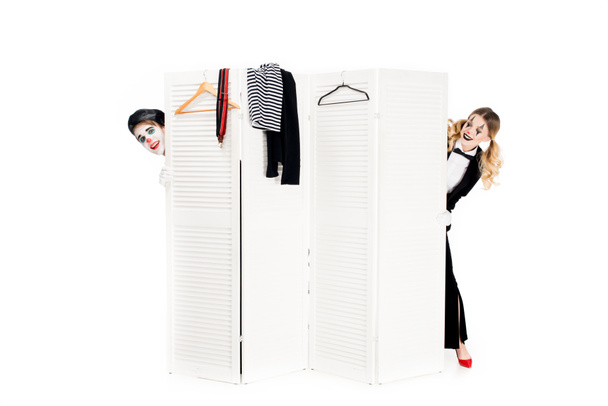 happy couple of clowns looking out from dressing room door isolated on white  - Foto, imagen
