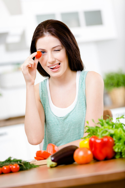 Mädchen hält Tomate am Tisch - Foto, Bild