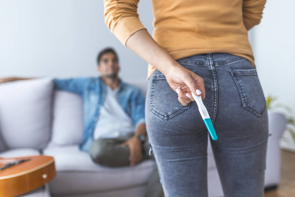 Close up of woman hiding pregnancy test for man - Фото, изображение