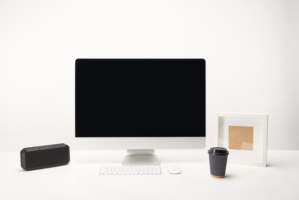 local de trabalho com café para ir, alto-falante portátil e computador desktop com espaço de cópia isolado em branco
 - Foto, Imagem