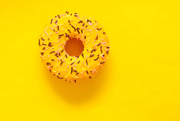 Delicious donut on bright yellow background. - Фото, изображение