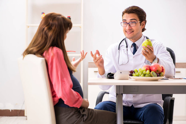 Pregnant woman visiting doctor discussing healthy diet - 写真・画像