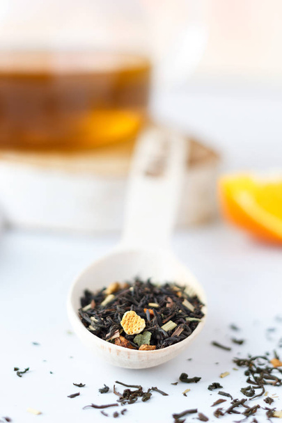 Τσάι μαύρο, διάσπαρτα με φλούδα πορτοκαλιού με ένα ξύλινο κουτάλι. - Φωτογραφία, εικόνα