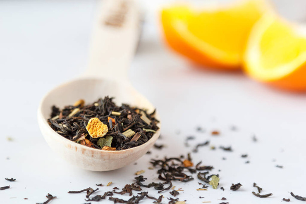 Чорний, розсіяний чай з апельсиновою шкіркою в дерев'яній ложці
. - Фото, зображення