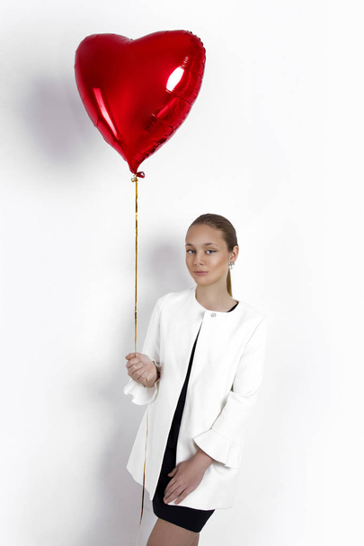 Valentine Beauty young girl, teenager with red air balloon portrait, isolated on background. Beautiful Happy Young kid holding balloons. Holiday party, birthday. Joyful little model - Image - Fotó, kép