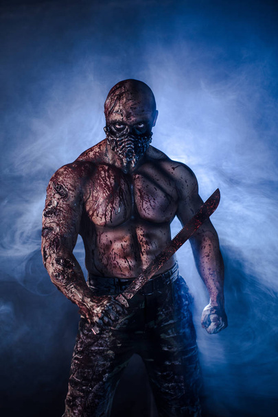 portrait of male zombie killer with machete against misty background - Zdjęcie, obraz