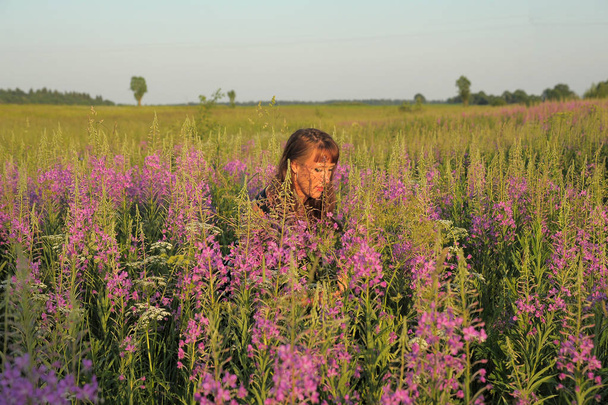 woman in a field with flowers Epilbium angustifolium in summer  - Φωτογραφία, εικόνα