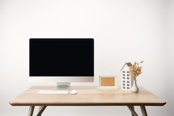 local de trabalho com modelo de casa, flores secas, moldura da foto e computador desktop com espaço de cópia isolado no branco
 - Foto, Imagem