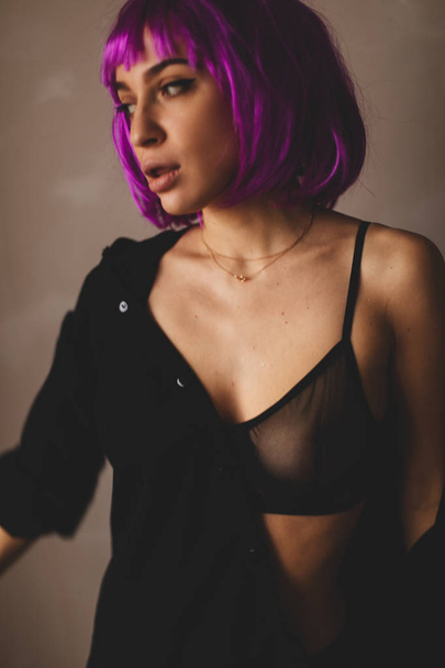 Attractive girl wear pink wig and black lingerie, shirt. Women close up a black shirt. Sexy girl taking off or putting on black shirt.  - Фото, изображение