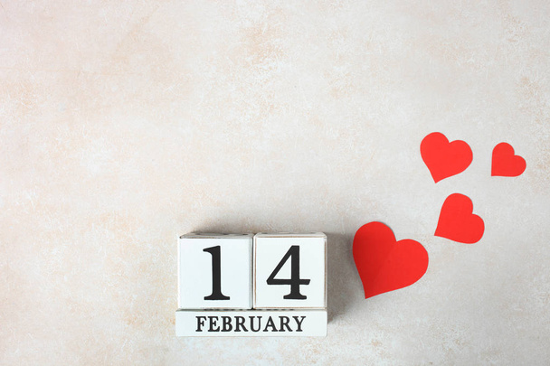 weißer Holzkalender mit Datum 14. Februar und kleinen roten Herzen auf neutralem Hintergrund. Konzept Valentinstag. - Foto, Bild
