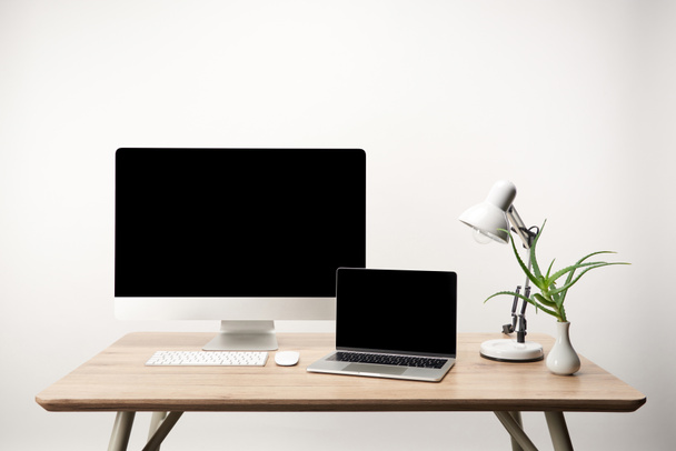 lugar de trabajo con lámpara, ordenador de sobremesa y portátil con espacio de copia aislado en blanco
 - Foto, Imagen