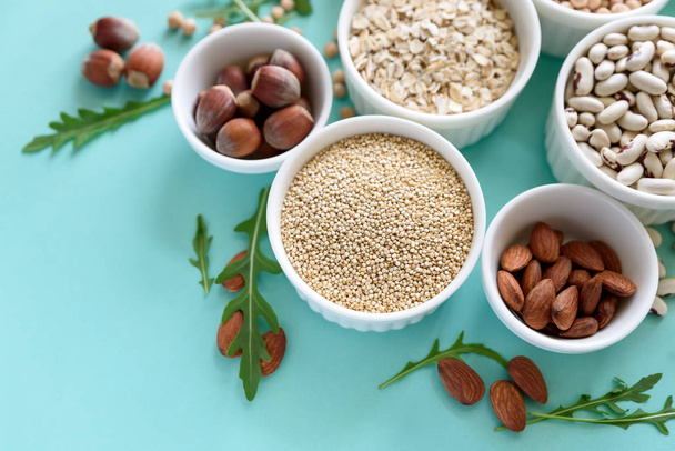 Set of bowls with organic quinoa, lentil, chickpea, wheat, walnut, almond, hazelnut and sesame. Cereals and legumes assortment on blue paper background. Top view. Copy space. Flat lay - Φωτογραφία, εικόνα