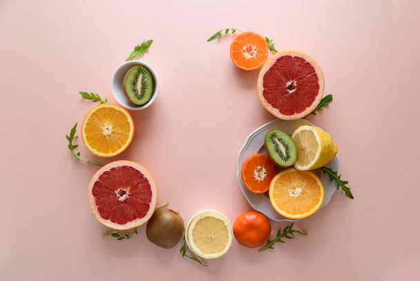 Tropical fruits frame from orange, lemon, tangerine and kiwi on pink paper background. Healthy food concept. flat lay. Top view - Foto, Bild