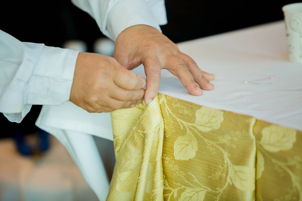Handen van personeel het tafelkleed met pin en decoratie voor de gasten voorbereiden - Foto, afbeelding
