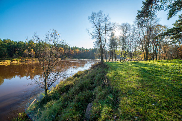 céu azul e nuvens que refletem na água calma do rio Gauja em latvia no outono. Caminhe na margem do rio. Dia de Outono limpo. visão de ângulo largo
 - Foto, Imagem