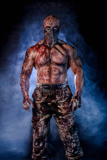 portrait of male zombie killer covered in blood posing against foggy background - Photo, image