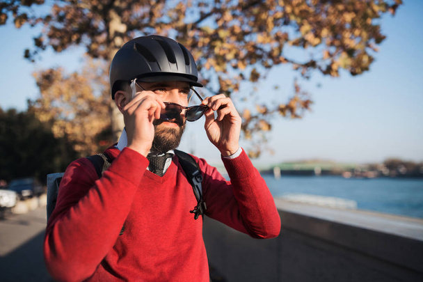 Businessman commuter with bicycle helmet and sunglasses on the way to work in city. - Φωτογραφία, εικόνα