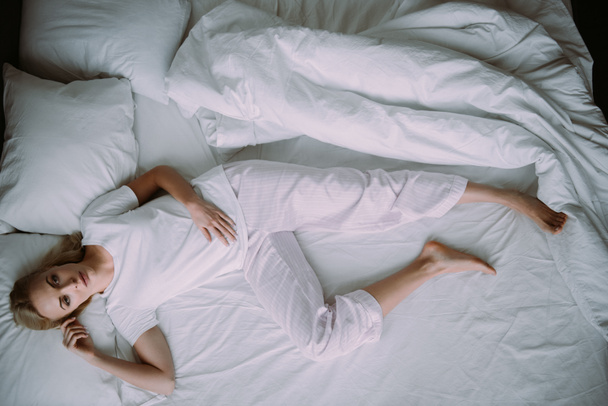 mujer deprimida en pijama acostada en la cama en casa
 - Foto, Imagen