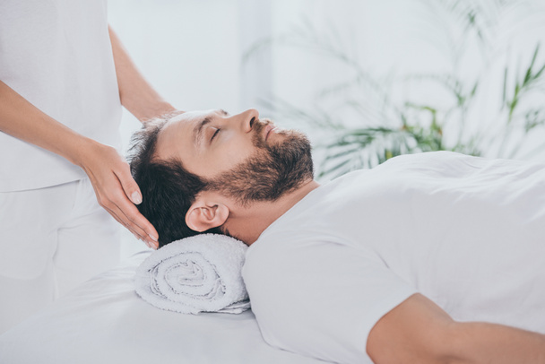cropped shot of man with closed eyes receiving reiki treatment - Fotografie, Obrázek