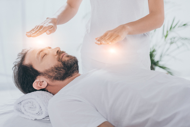 cropped shot of bearded man with closed eyes receiving reiki healing treatment - Photo, Image