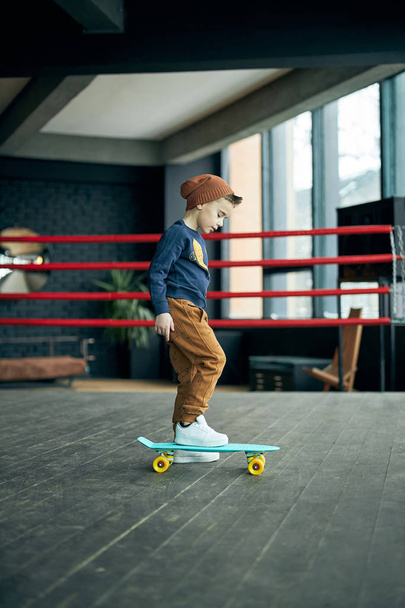 Little stylish boy skateboarding on boxer ring - Foto, Imagen