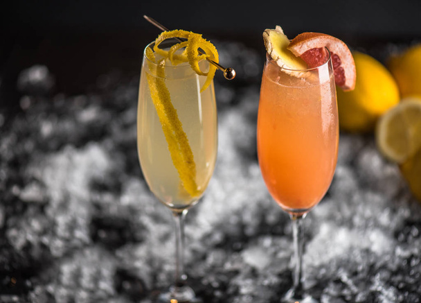 Cocktails in glasses decorated with fruit slices on dark background with ice - 写真・画像