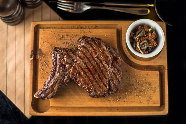 Grilled steak served on wooden board with rosemary - 写真・画像