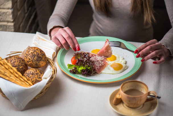 zbliżenie: kobieta o stole śniadanie z jajkiem sadzonym, szynką i świeże warzywa - Zdjęcie, obraz