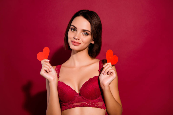 Close-up portrait of nice cute chic attractive lovely tender winsome gorgeous lady girlfriend holding in hands two small hearts isolated over burgundy maroon background - Photo, image