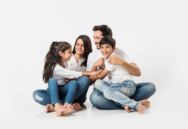 Young Indian family sitting isolated over white background. selective focus - Фото, изображение