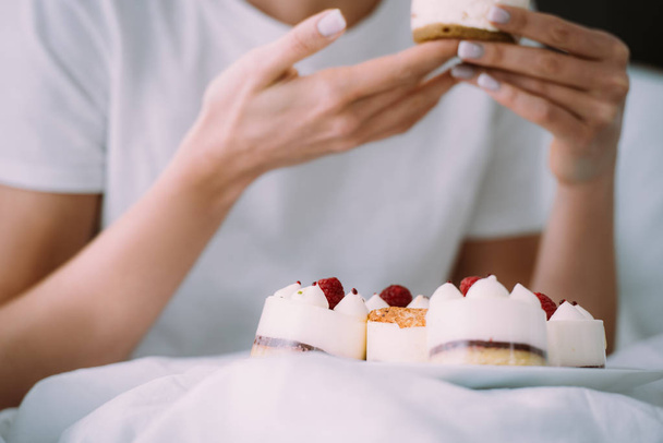 cropped view of woman eating cake in bed - Foto, Imagen
