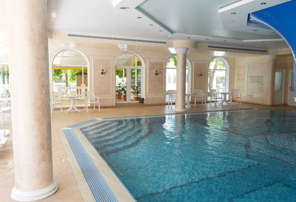 Luxusní design bazénu, sluneční světlo z panoramatických oken, stylové sloupy a tyrkysová voda. - Fotografie, Obrázek