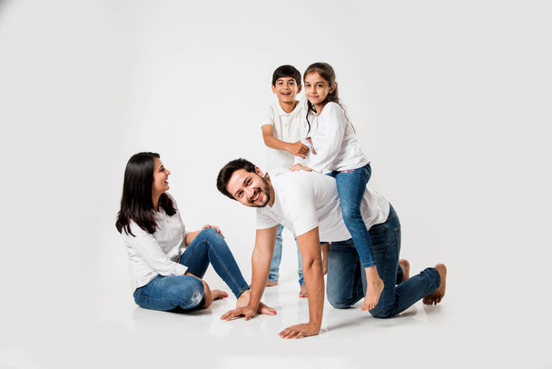 joyeuse fille monter sur le dos du père. Petite fille indienne assise sur le dos de papa pendant que maman et frère riaient. focus sélectif - Photo, image