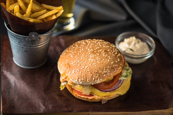 Tasty burger with french fries on wooden board - Фото, изображение