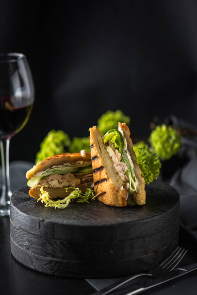 Chicken fried sandwich with vegetables served on board on dark background - Valokuva, kuva