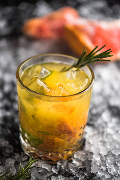 Cocktail lasi greippi ja rosmariini tummalla pohjalla jäällä
 - Valokuva, kuva