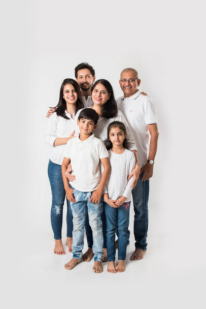 Famiglia indiana isolata su sfondo bianco, coppia anziana e giovane con bambini che indossano top bianco e blue jeans. focus selettivo - Foto, immagini
