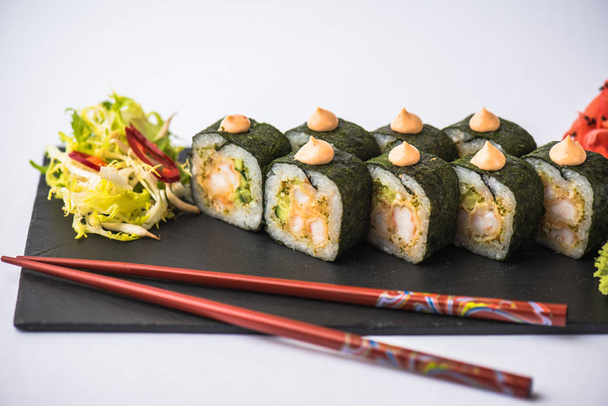 Japanese sushi roll served on slate on white background - Foto, afbeelding