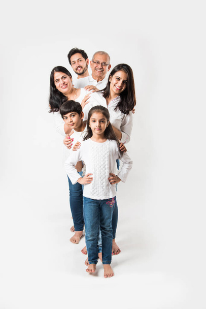 Indiánská rodina stojí izolovaně nad bílým pozadím, starší a mladý pár s dětmi v bílém tričku a modrých džínách. selektivní zaměření - Fotografie, Obrázek