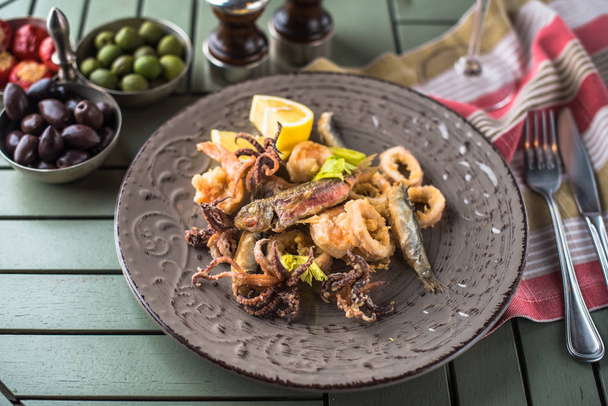 Plate of fried seafood on wooden table with appetizers - Valokuva, kuva