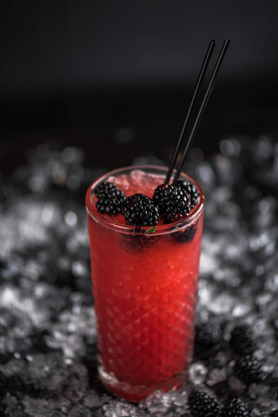 Cocktail with fresh blackberries in glass on ice in dark background - Zdjęcie, obraz