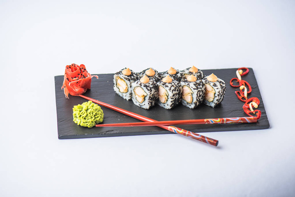 delicious japanese sushi roll with wasabi, ginger and chopsticks on slate board on grey background    - Photo, image