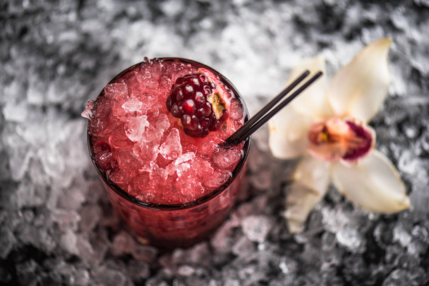 Cocktail in glass with pomegranate on dark background with ice - Foto, imagen