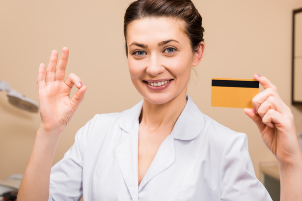 косметолог тримає кредитну картку і показує хороший знак в салоні краси
 - Фото, зображення