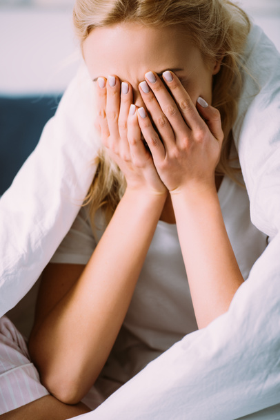 selective focus of woman in blanket covering face with hands and crying in bed at home  - Photo, Image
