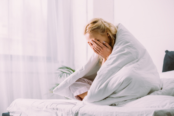 mujer en manta cubriendo la cara con las manos y llorando en la cama en casa
  - Foto, Imagen