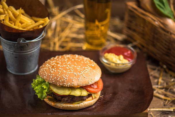 Tasty burger with french fries on wooden board - Фото, зображення
