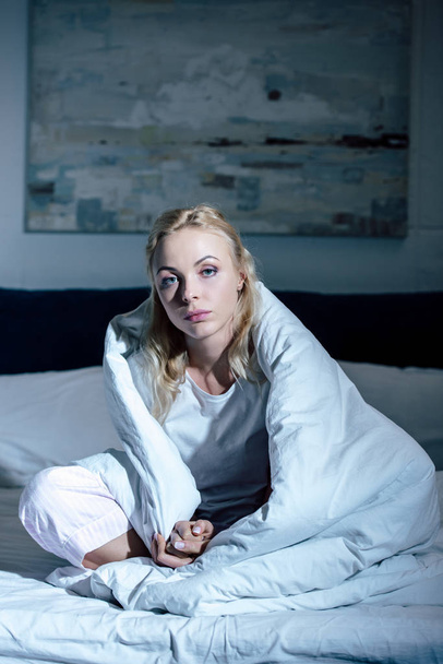 ideges nő borított takaró ül ágyas és látszó-on fényképezőgép otthon - Fotó, kép