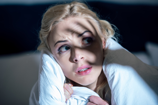 selective focus of frightened woman covered in white blanket looking away - Photo, Image