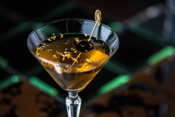 Alcohol cocktail in glass decorated with olive on stick - Photo, Image
